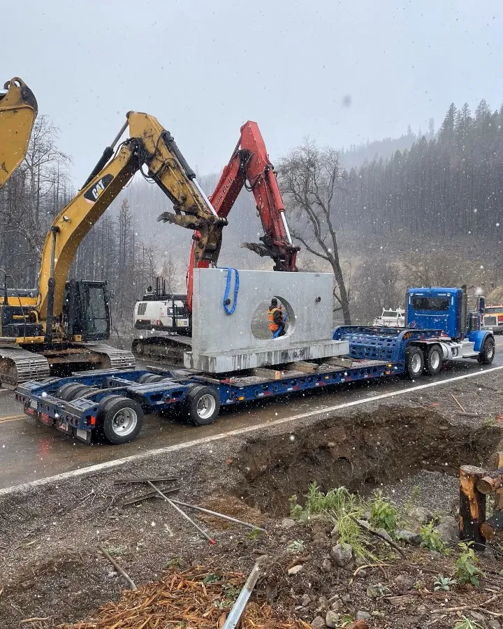 Excavators loading a precast concrete headwall